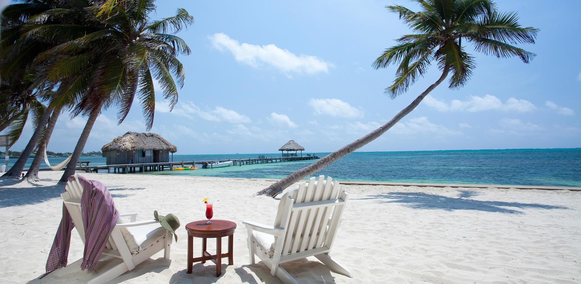 Seating on white sand beach amongst palm trees, Victoria House Resort & Spa, The Cayes, Belize, Central America