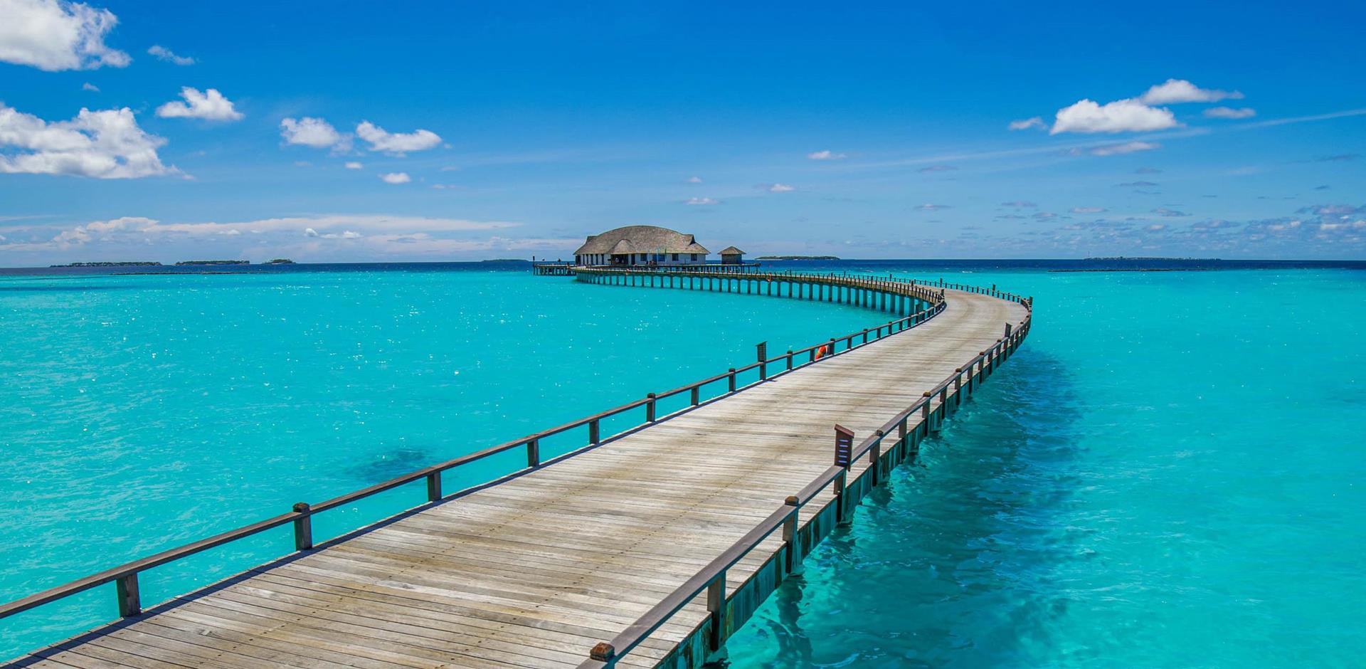 Long pier across tropical lagoon reaching water villas, Maldives, Indian Ocean